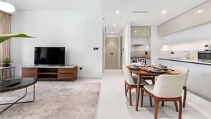 A modern kitchen with a dining area, a TV, and a plant. - Stayshort - 1 Bedroom in Emaar Beachfront That Sleeps 4 (Dubai)