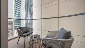 A balcony with wicker furniture and a view of high-rise buildings. - Stayshort - 1 Bedroom in Emaar Beachfront That Sleeps 4 (Dubai)