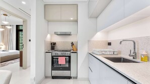 A modern kitchen with white cabinets, a stainless steel stove, and a sink. - Stayshort - 1 Bedroom in Emaar Beachfront That Sleeps 4 (Dubai)
