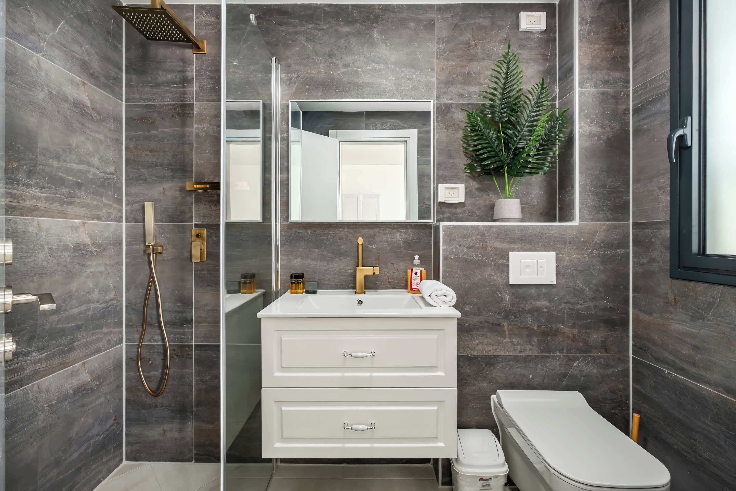 Een moderne badkamer met een witte wastafel, douche en toilet.