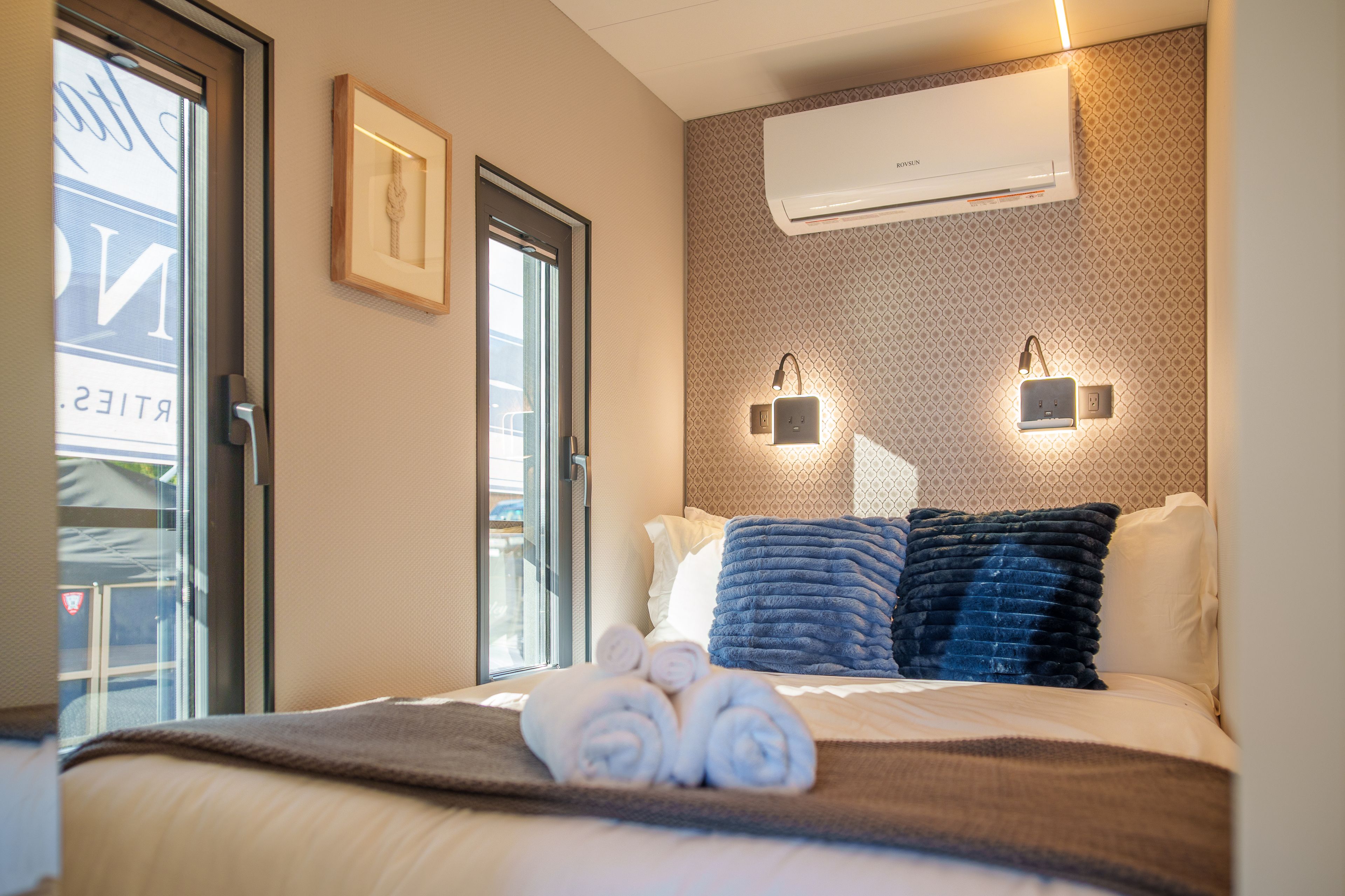 Une chambre d’hôtel équipée d’un lit, d’une fenêtre, d’un appareil de climatisation et d’un luminaire fixé au mur.
