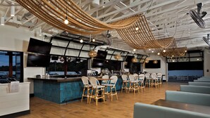 A modern restaurant with a bar area, wooden flooring, and a view of the outside.
