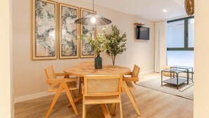Un coin repas avec une table ronde en bois, six chaises, un vase de fleurs et trois œuvres d’art encadrées accrochées au mur.
