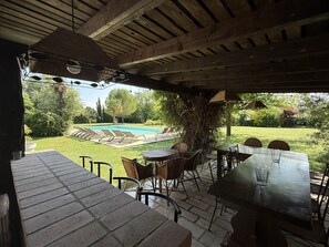 Un espace extérieur aménagé en terrasse, avec une piscine, des meubles en osier et une vue sur le jardin arrière.