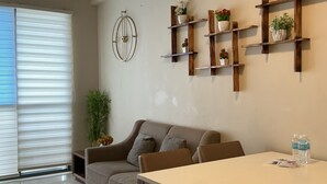 Uma sala de estar moderna com um sofá, uma mesa de jantar e estantes de madeira com plantas.