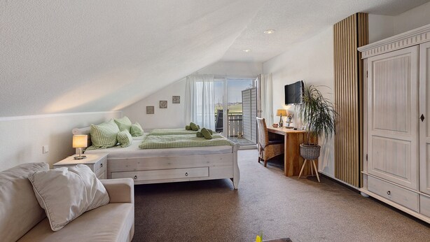 Une chambre à coucher avec un lit, un bureau, une armoire et une vue par la fenêtre.