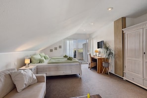 Une chambre à coucher avec un lit, un bureau, une armoire et une vue par la fenêtre.