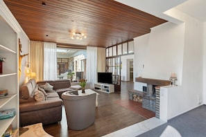 Ein modernes Wohnzimmer mit Holzboden, einem Fernseher, einem Kamin und einer Sitzecke.