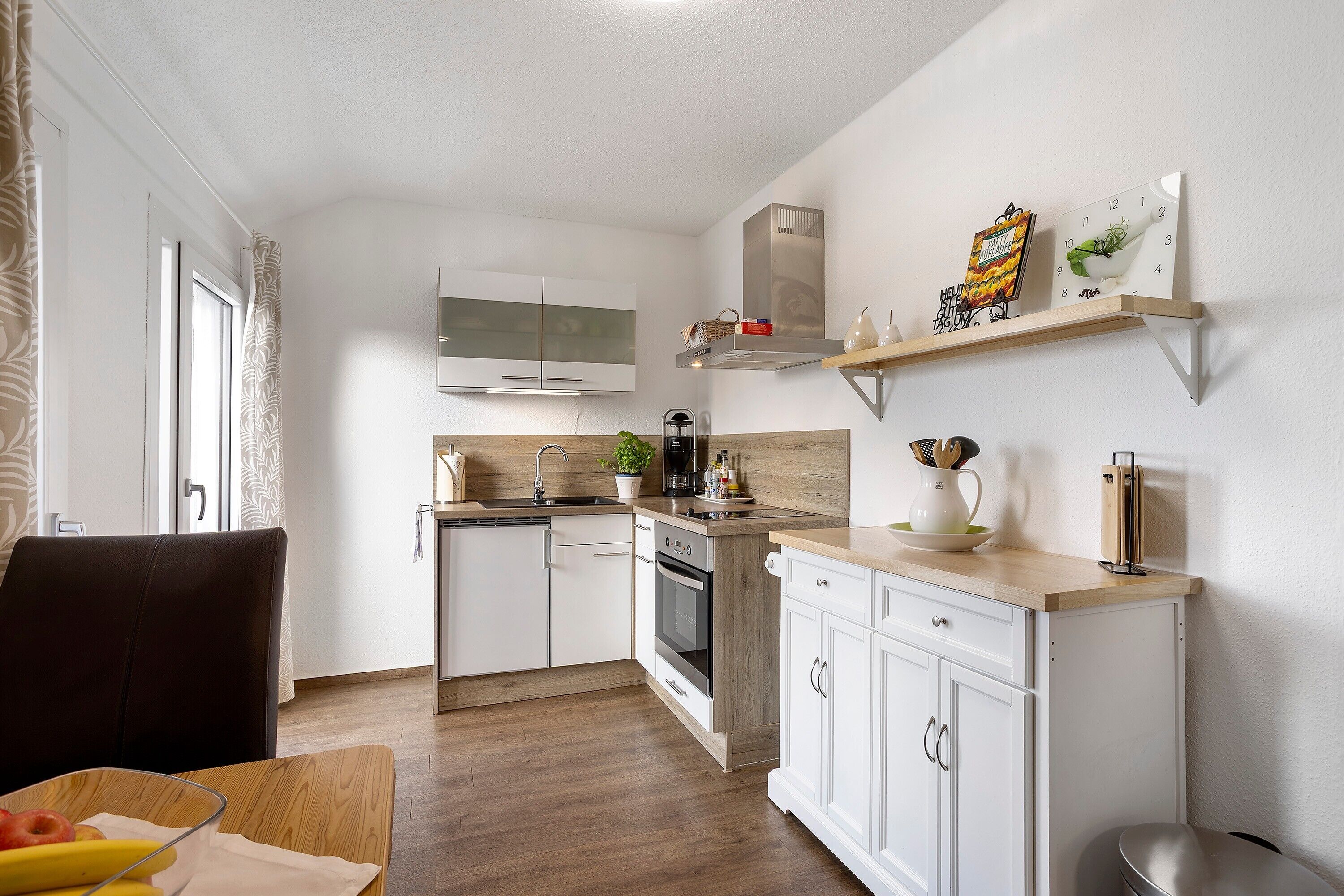 A modern kitchen with white cabinets, a wooden countertop, a built-in oven, and a microwave.