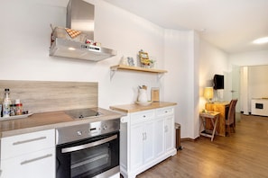 A modern kitchen with a built-in oven, a stainless steel range hood, white cabinetry, and a wooden countertop. - Apartment 'Ferienwohnung Seeblick' with Lake View, Balcony and Wi-Fi (Möhnesee)