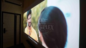 A cinema screen with a movie playing, featuring a man in a yellow shirt. - Hotel Cineplex (Coimbatore)