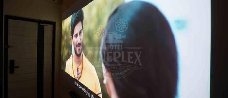 Una pantalla de cine mostrando una película, con un hombre con una camisa amarilla.