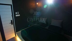 A hotel room with a bed, a wall-mounted projector, and a door. - Hotel Cineplex (Coimbatore)