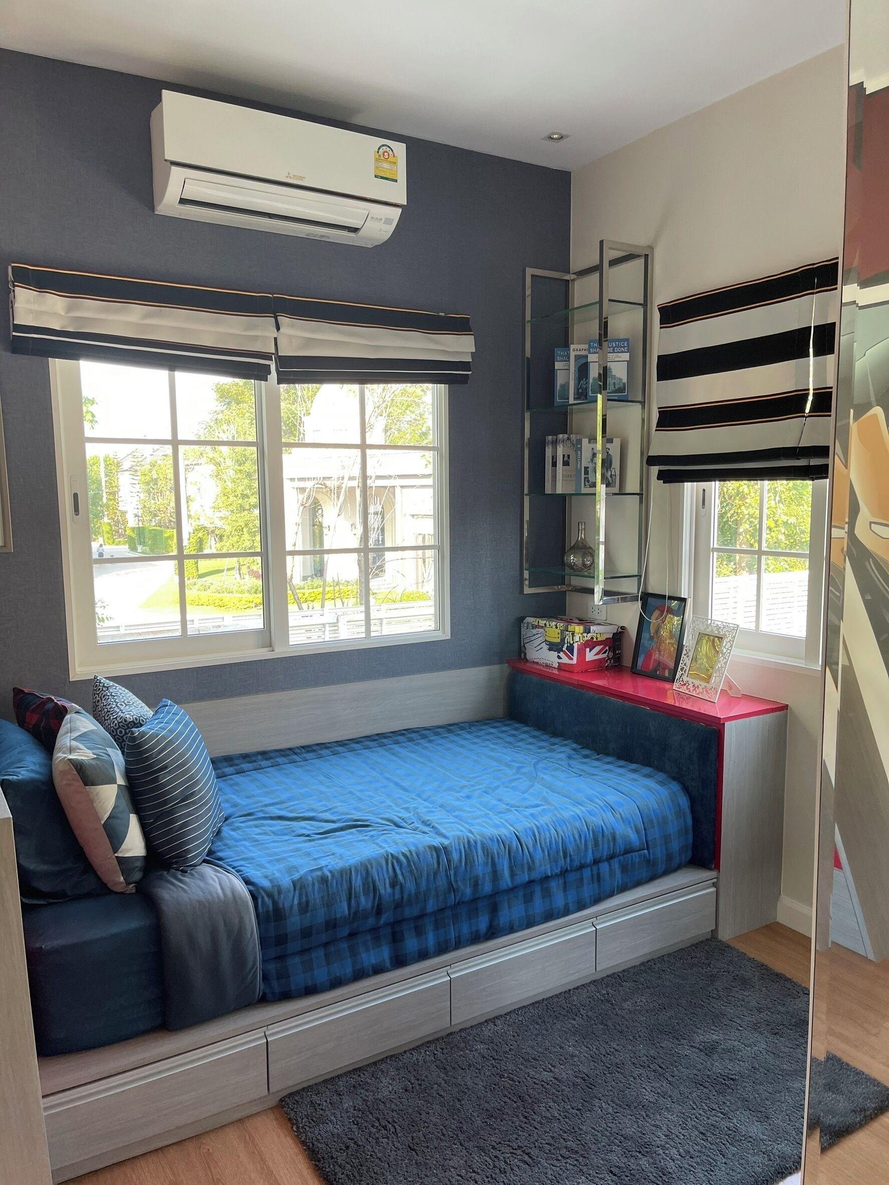 A compact bedroom with a single bed, a small desk, and a window.
