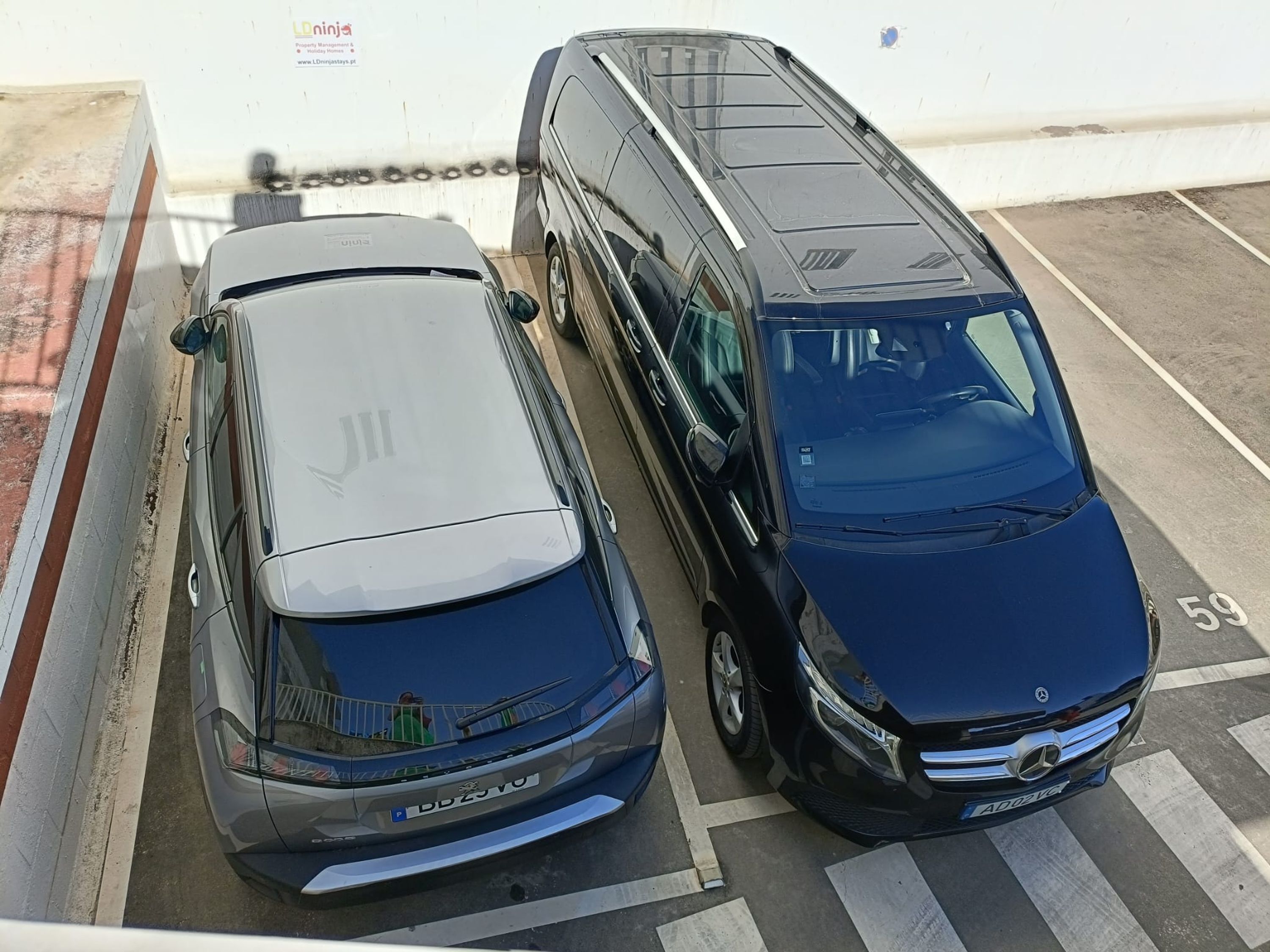 Dois carros estacionados lado a lado num parque de estacionamento.