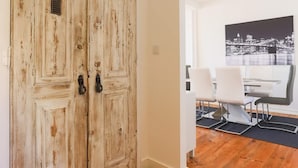 Une pièce dotée d’un plancher en bois, d’un mur blanc et d’une porte à deux vantaux au style rustique.