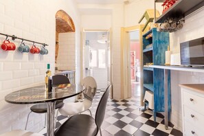 A compact kitchen with a checkered floor, a round table with chairs, and a row of colorful mugs on the wall. - Artistic Alfama 4BR Cathedral Views Tram 28 (Lisbon)