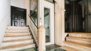 A staircase with a glass balustrade and a door leading to an elevator. - Artistic Alfama 4BR Cathedral Views Tram 28 (Lisbon)