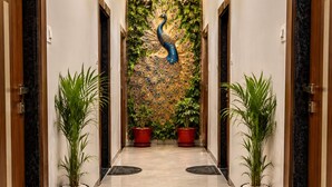 A hallway with a peacock mural, potted plants, and marble flooring.