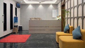 A modern lobby with a reception desk, seating area, and a water dispenser.