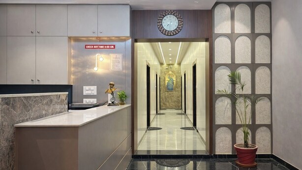 A hotel reception area with a marble counter, a clock, and a check-out time sign.