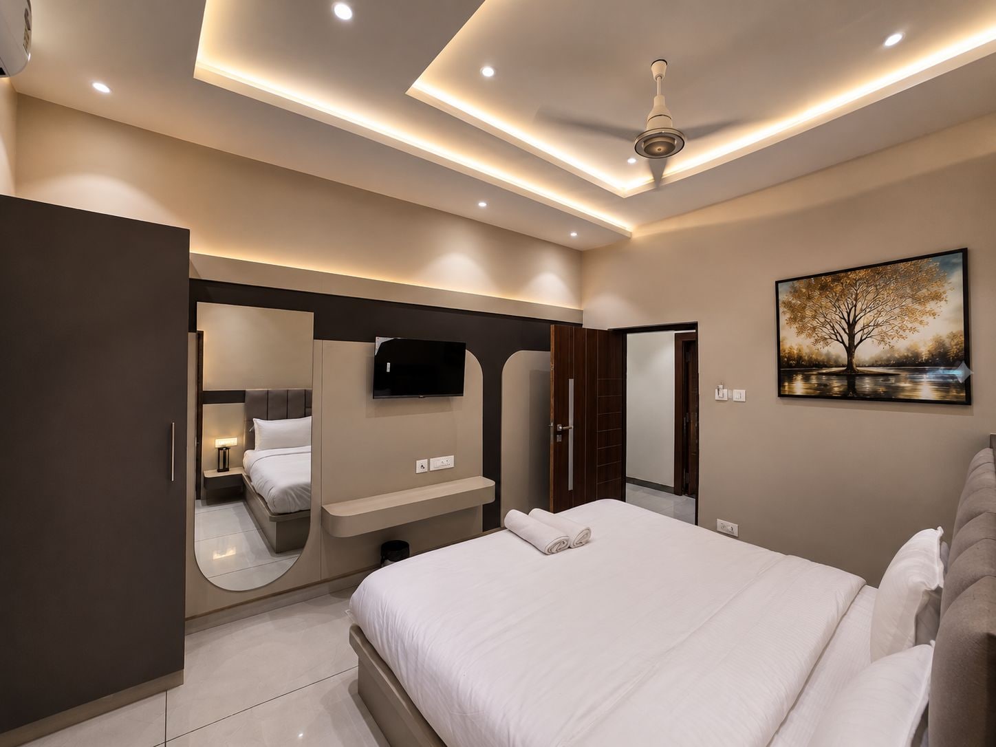 Un dormitorio moderno con cama, televisor, espejo y un cuadro.