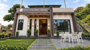A modern villa with a prominent entrance, a flag, and a staircase leading to the upper level.