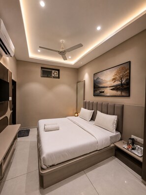 A modern bedroom with a bed, bedside table, and a ceiling fan. - HOTEL GEETANJALI (Mount Abu)