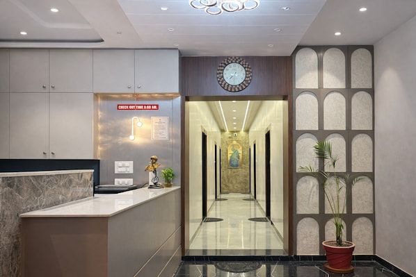 A modern reception area with a marble counter, a clock, and a check-out sign.
