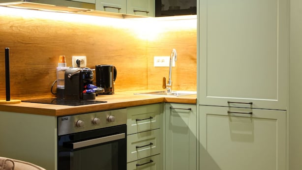 Une cuisine compacte équipée d’un four encastré, d’une machine à café et d’un évier.