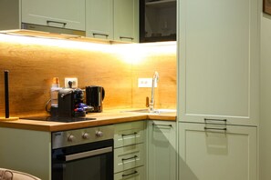A compact kitchen with a built-in oven, a coffee maker, and a sink. - Grandstay Urban Nine (Durrës)