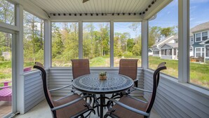 Ein überdachter Patio mit einem runden Tisch und vier Stühlen, mit Blick auf eine Wohngegend mit Häusern und Bäumen.
