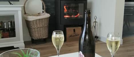 A cozy living room with a fireplace, two glasses of wine, and a bottle of whisky on a placemat.