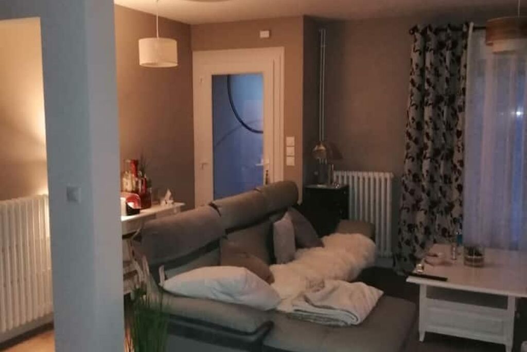 Sala de estar con sofá, una mesita, un radiador y una puerta decorada con un diseño azul.
