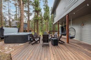 Puuinen terassi, jossa on ulkokalusteita, poreallas ja grillauspaikka.
