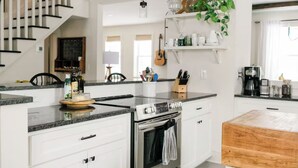 Une cuisine moderne avec des meubles blancs, un four encastré et une table à manger en bois.