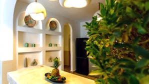A modern kitchen with white cabinetry, a black refrigerator, and decorative wall art. - Riad KAMA privatif (Marrakech)