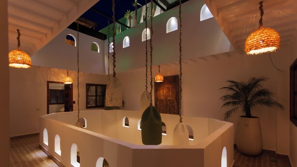 A modern interior with a central island, hanging lights, and a large potted plant. - Riad KAMA privatif (Marrakech)