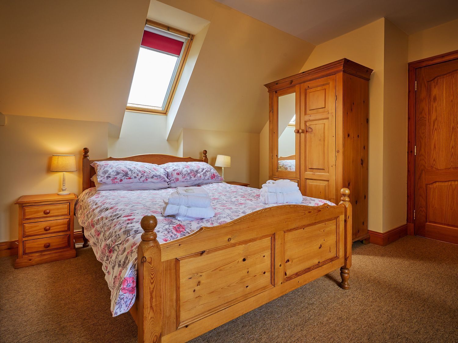 Une chambre avec un lit en bois, une table de chevet, une armoire et un puits de lumière.