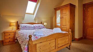 Une chambre avec un lit en bois, une table de chevet, une armoire et un puits de lumière.