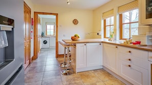 A kitchen with a washing machine, a sink, a fruit bowl, and a microwave. - Holly House (Blairgowrie)