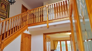 A wooden staircase leading to an upper level, with a view of a living room and a glass door. - Holly House (Blairgowrie)