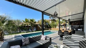 Un área exterior moderna con piscina, mobiliario y vistas del paisaje circundante.