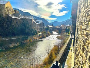 A river flowing through a town with stone buildings and a bridge. - Hotel La Creu by RdA Hotels (Esterri D'Aneu)