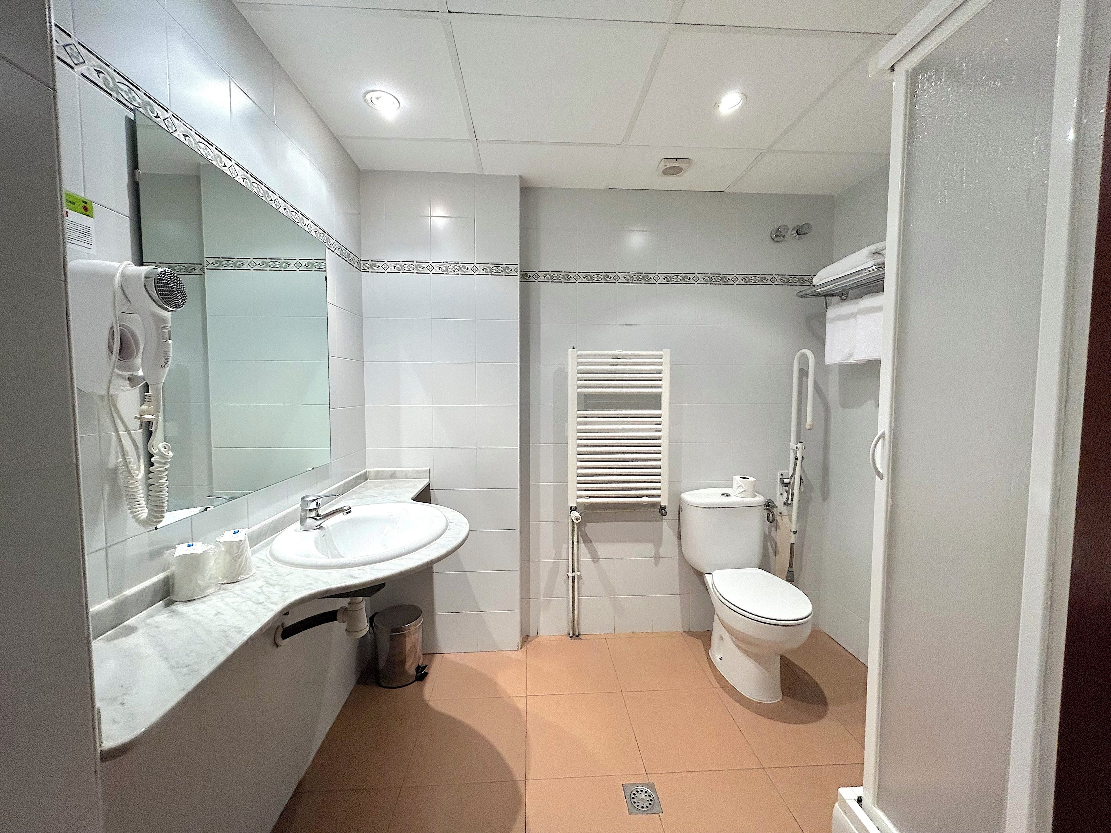 Ein Badezimmer mit Waschbecken, Spiegel, Toilette und Handtuchhalter.