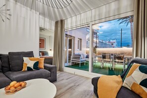 A modern living room with a sofa, a coffee table, and a dining area with a table and chairs. - Beachfront Conquistador (El Campello)