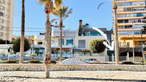 Een pand aan het strand, met moderne architectuur, palmbomen en een heldere lucht.
