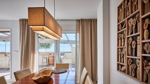 Een eethoek met een houten tafel, stoelen, een hanglamp en een muur met houtsnijwerk.