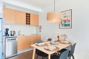 Une cuisine moderne avec des meubles en bois, un four encastré et un coin repas avec une table dressée pour deux personnes.