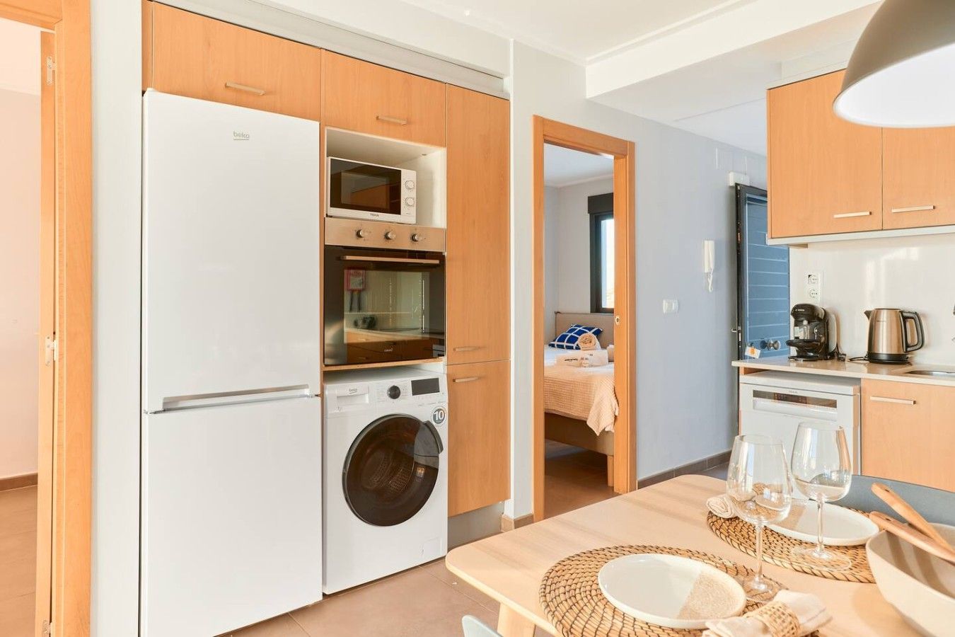 Cozinha compacta equipada com geladeira, micro-ondas, forno e máquina de lavar.